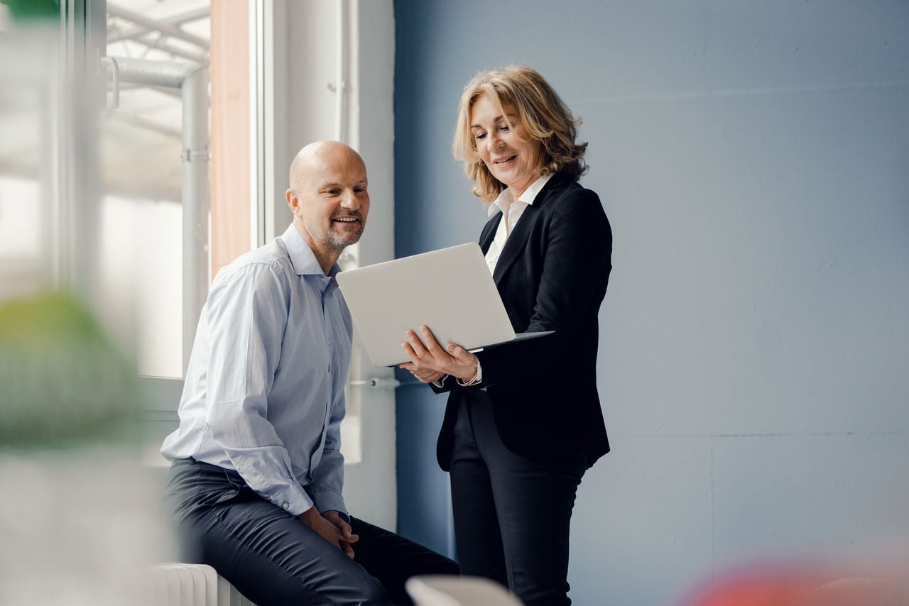 Photo of a man and a woman looking at the laptop