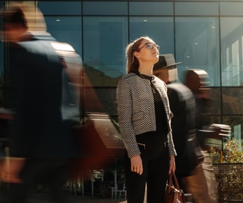Image of a person among busy people stopping and looking at a building 
