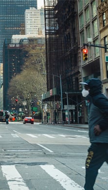 Image of  a man in a mask crossing an empty times square street 