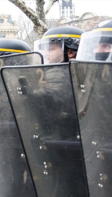 Photo of a barricade of police officers wearing shields and helmet